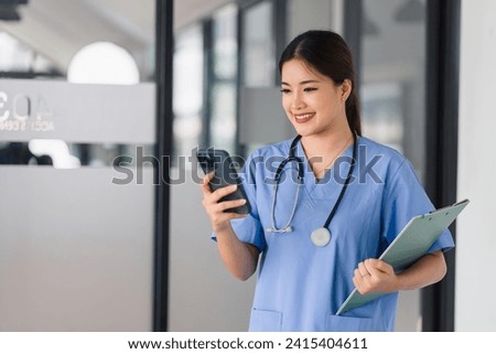 Asian Nurse with Smartphone and Clipboard on Hospital Shift Royalty-Free Stock Photo #2415404611