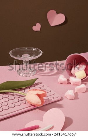 Adorable keyboard with a tulip flowers placed on, arranged with crayons, heart papers and a cup filled with marshmallows. Pink valentines or anniversary background