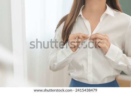 Get dress, beautiful asian young woman, businesswoman standing buttoning white shirt formal getting dressed, ready before go to work looking reflection the mirror in bedroom in the morning at home. Royalty-Free Stock Photo #2415438479
