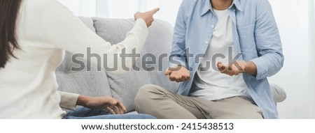 Infidelity, suspicion asian young couple love fight relationship, wife holding cellphone, smartphone cheating on phone, scolding husband about mistrust, distrust and jealousy when sitting at home. Royalty-Free Stock Photo #2415438513
