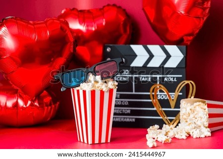 A banner for the film industry. A romantic movie date. A movie camera, 3D glasses, popcorn and heart-shaped foil balloons on a red background. The premiere of the film is on Valentine's Day. Royalty-Free Stock Photo #2415444967