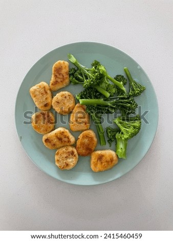 Interior top view photo of a simple lunch dinner meal made from fried chicken nuggets with boiled green healthy brocoli vegetable veggies redy to be eaten