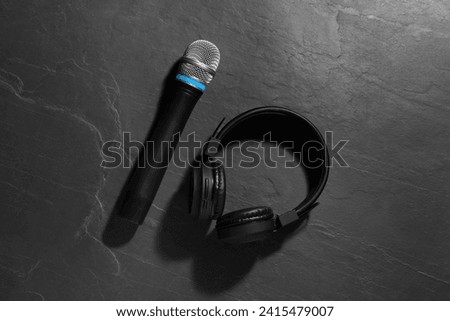 Microphone and headphones on grey textured background, flat lay. Sound recording and reinforcement