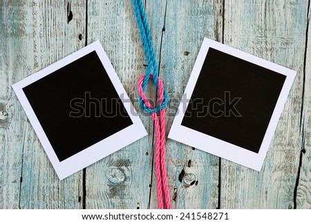 Reef knot and instant photo frames on old wooden table