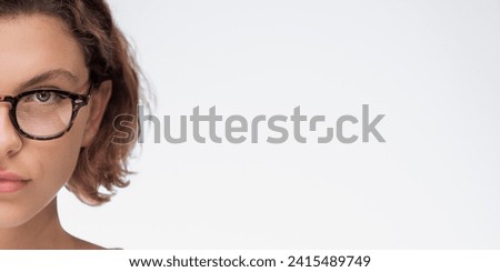 Beautiful half face woman in glasses looks into the camera isolated on white background. High quality banner photo