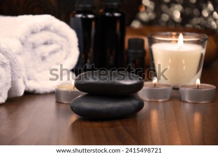 Spa massage hot stones, white towels and candles on wooden background still life stock photo images. Spa and wellness setting with towels, candles and pebbles. Beauty spa treatment composition images