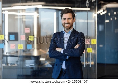 Portrait of successful businessman inside office in business suit, man with crossed arms smiling and looking at camera, experienced financier boss near window, investor. Royalty-Free Stock Photo #2415508407