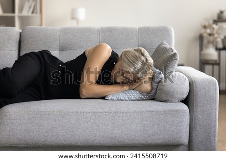 Mature woman resting on sofa take nap in living room. Unhappy middle-aged single female lying down on couch feel stressed, unhappy after break up, fight, going through divorce, coping with depression Royalty-Free Stock Photo #2415508719