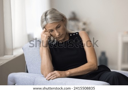 Sad melancholic mature woman sit alone at home deep in thoughts, thinking about personal life troubles, unrealized goals, marriage split feel unhappy and lonely. Middle age crisis, divorce, nostalgia Royalty-Free Stock Photo #2415508835