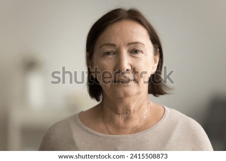 Indoor head shot portrait of serious positive old mature woman in casual looking at camera, posing at home, promoting retirement, elderly healthcare. Senior grandmother woman video call screen