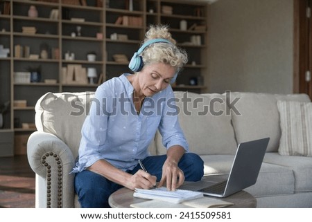 Focused mature woman e-learns using modern wireless tech, studying, gain knowledge, improve develop language skills, receive new knowledge, learning, planning use laptop and headphones. Self-education Royalty-Free Stock Photo #2415509581