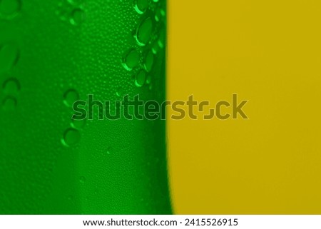 Photograph of water drops in a clear glass The background is green and yellow.