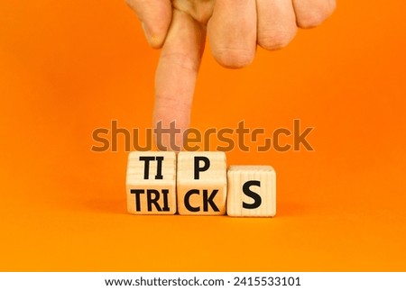 Tips and tricks symbol. Turned wooden cubes and changed the word tricks to tips. Beautiful orange table, orange background. Businessman hand. Business, tips and tricks concept. Copy space.