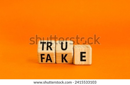 Fake or true symbol. Turned wooden cubes and changed the word fake to true or vice versa. Beautiful orange table, orange background, copy space. Business and fake or true concept.