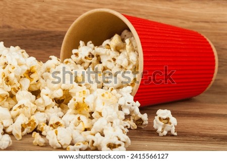 Popcorn in red glasses on a wooden background. Detail for design. Design elements. Macro. Background for business cards, postcards and posters.