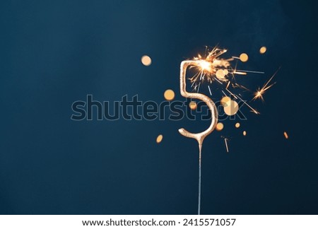 5 years celebration festive background with copy space made with Bengal fire in the form of number Five. Royalty-Free Stock Photo #2415571057
