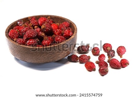 Rosehip berries isolated inside and outside the wooden bowl on a white background. Royalty-Free Stock Photo #2415574759