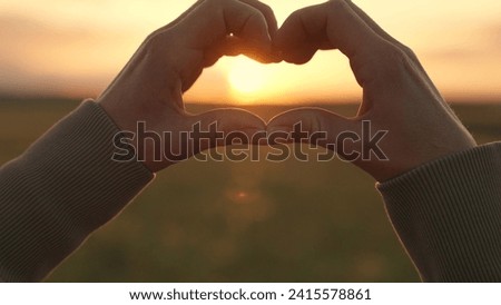 Young woman loves to travel. Girl molded love heart from her palms. Happy girl making heart shape with fingers. Light of summer spring sun is in my hands. Travel relax in nature. Healthy heart concept