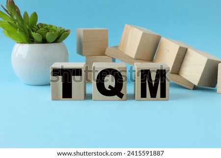 blue background. wooden cubes with text. Total Quality Management TQM Royalty-Free Stock Photo #2415591887