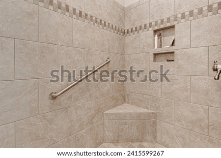 Spacious Tiled Walk-In Shower with Built-In Bench, Safety Grab Bar, and Recessed Shelf in a Luxurious Beige Toned Bathroom Royalty-Free Stock Photo #2415599267