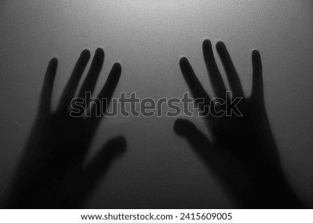 Silhouette of creepy ghost behind glass against grey background, closeup