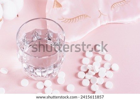 Good sleep concept, sleeping pills, glass of water and sleep mask on pink background Royalty-Free Stock Photo #2415611857