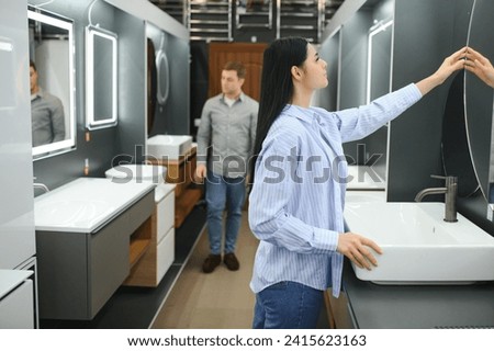 Young family couple choosing bathroom sink in bathroom fixtures store.
