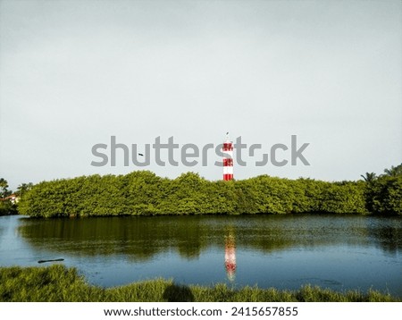 Red and white Vypin lighthouse surrounded by Mangrove plants in Kochi, Kerala India. Puthuvype Lighthouse view. Royalty-Free Stock Photo #2415657855