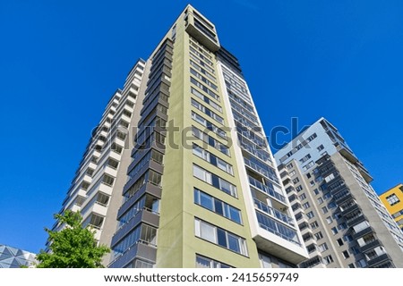 A high-rise building with an abundance of windows and vibrant green trim along the exterior facade Royalty-Free Stock Photo #2415659749