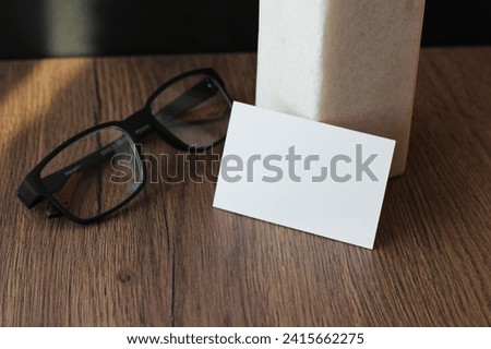 Empty business card mockup with glasses on wooden table background. Mock up for branding identity. Blank template for your design.