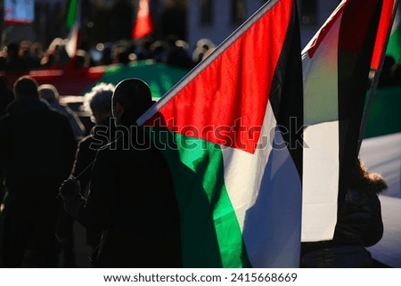 many Palestinian backlit flags carried by demonstrators during the protest march for freedom and independence Royalty-Free Stock Photo #2415668669