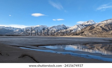 Foothills of Jasper National Park in Alberta, Canada. Early morning mist with the lower side of the mountains with peaks covered in snow as the river is half frozen and misty. Royalty-Free Stock Photo #2415674937