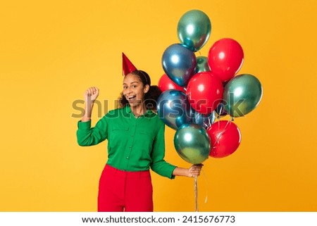 Birthday party and surprises. Cheerful black teen girl holding bunch of bright balloons, gesturing yes celebrating her bday joyfully against yellow studio backdrop. Holiday celebration