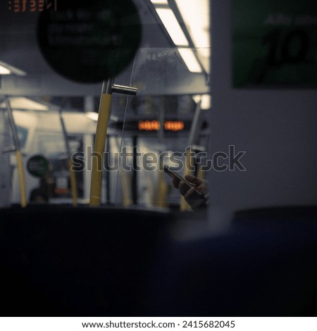A picture Inside the train towards Central Stockholm City. A stranger on their phone, standing in the train