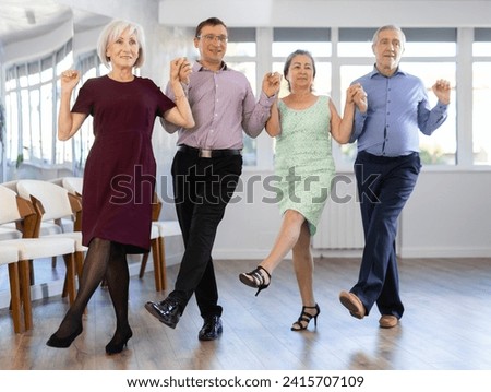 Positive adults forming line while rehearsing traditional Irish stepdance in modern dance studio