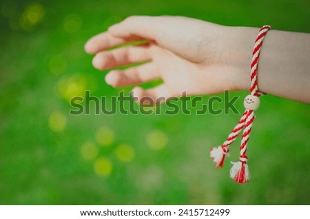 Selective focus of hand with traditional bracelet on green grass background 