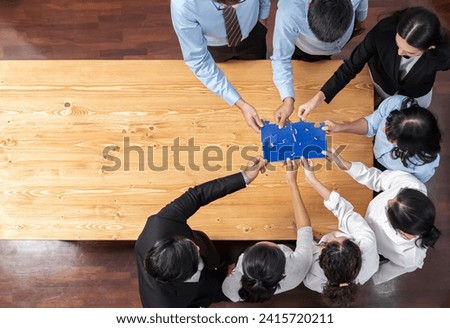 Multiethnic business people holding jigsaw pieces and merge them together as effective solution solving teamwork, shared vision and common goal combining diverse talent. Panorama top view. Meticulous Royalty-Free Stock Photo #2415720211