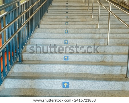 view of public staircase with railing in the middle dividing the direction of up and down.
