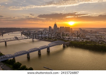 Cincinnati city, Ohio, USA with bridge highway traffic driving cars in downtown district. American city skyline with brightly illuminated high commercial buildings at sunset
