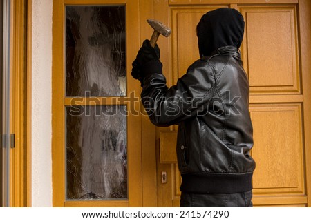 Burglar destroying a front door Royalty-Free Stock Photo #241574290