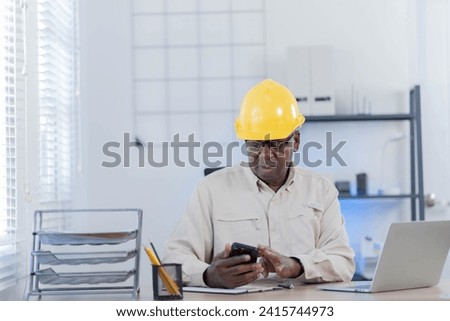 Professional of man architect industrial engineer sitting in the office, foreman in helmet using laptop working with new construction project architectural plan.