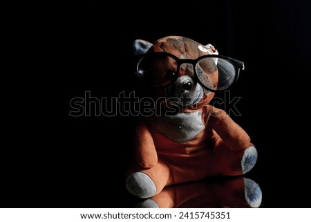 close up of teddy bear wearing glasses in low light