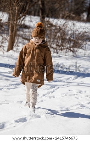 Funny little boy  walks during a snowfall. Outdoors winter activities for kids. 