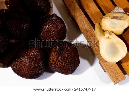 some snake fruit with brown skin and some that have been peeled with wooden coasters