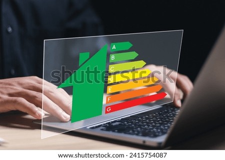 Energy efficiency concept. Person use laptop with virtual screen of energy efficiency rating for energy efficient house building rate label audit.