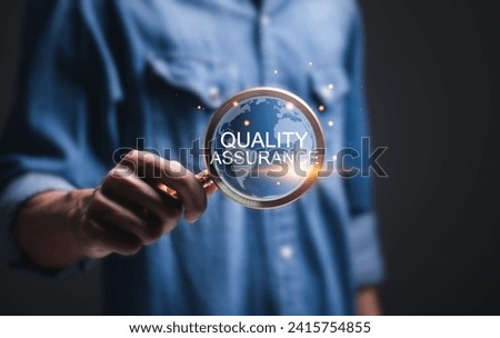 Quality assurance service guarantee standard concept. Businessman use magnifying glass focus to virtual  quality assurance word.