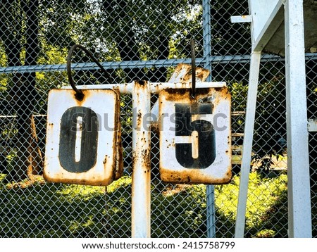 Closeup view of tennis scoreboard, rusty but still in use. Current tennis score: 0-5.  Royalty-Free Stock Photo #2415758799