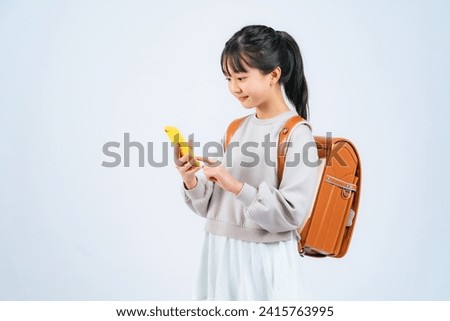 An elementary school girl using a smartphone. Royalty-Free Stock Photo #2415763995