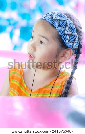 A cute little Asian girl in an orange dress is showing emotions and gestures.