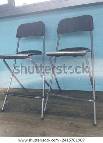 Close up photo view of 2 black bar chairs side by side together as a pair twin double furniture in wood to sit on